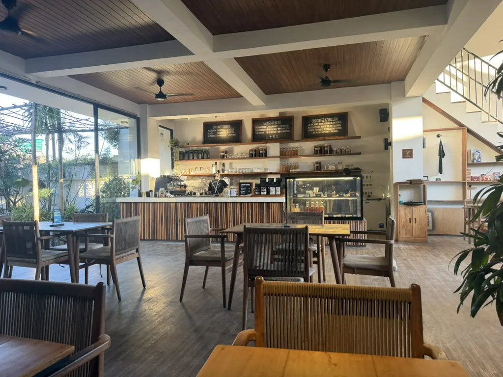 Curfew's open-air coffee bar in Kuta Lombok — timber ceiling, chalkboard menus, and garden light pouring in
