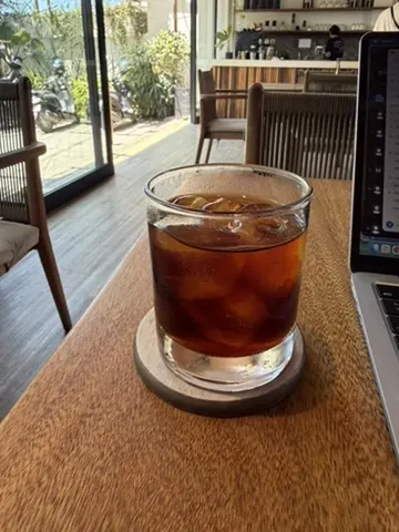 A rocks glass of cold brew over ice on a wooden coaster at Curfew's bar